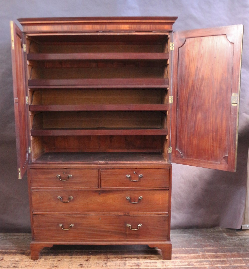 A Georgian mahogany linen press featuring panelled double doors above a chest with two short and two long drawers raised on bracket feet. View III