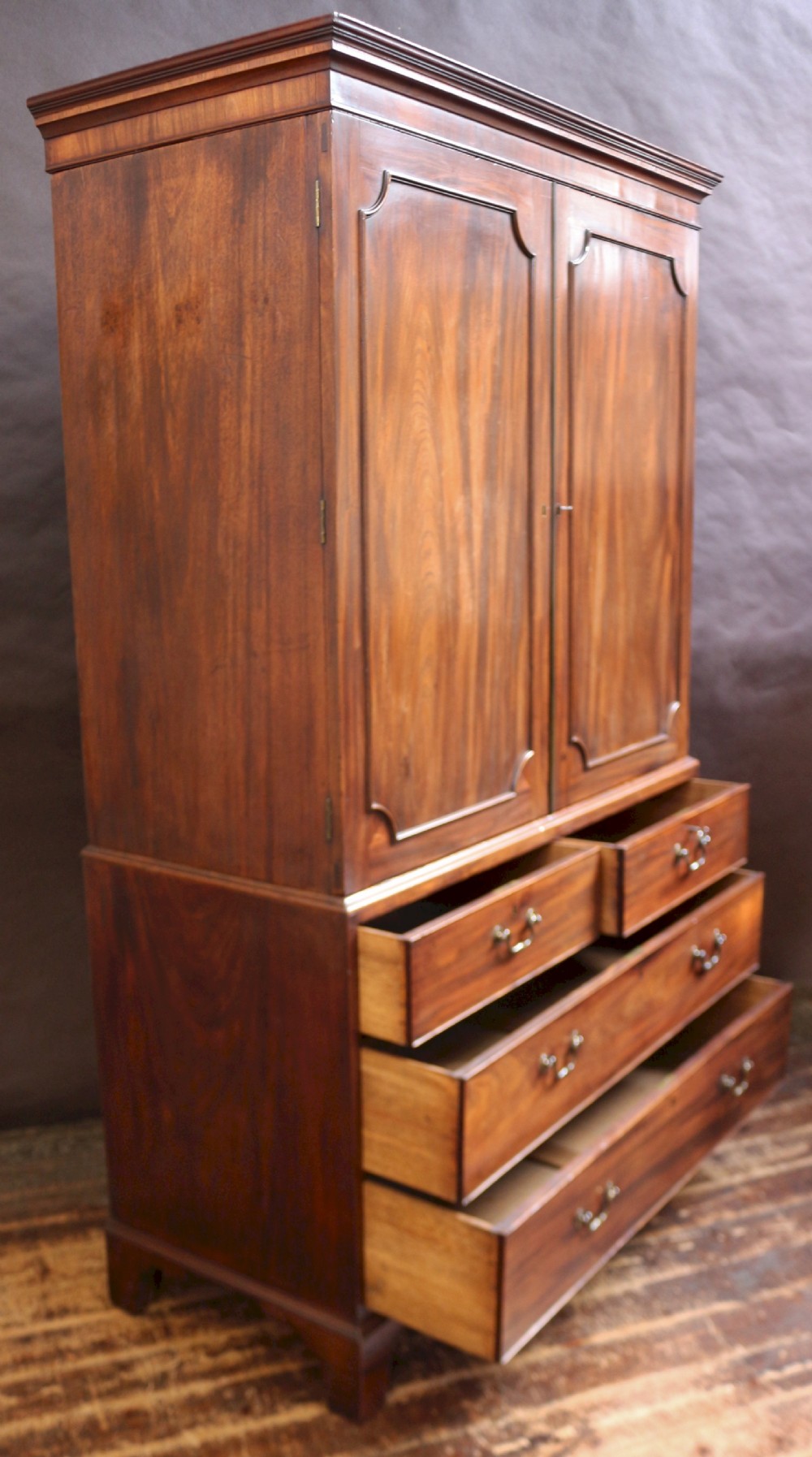 A Georgian mahogany linen press featuring panelled double doors above a chest with two short and two long drawers raised on bracket feet. View V