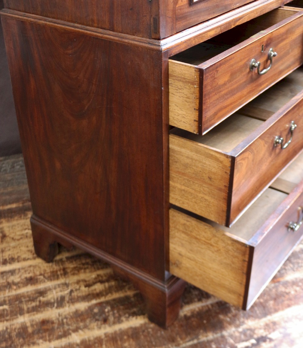 A Georgian mahogany linen press featuring panelled double doors above a chest with two short and two long drawers raised on bracket feet. View VI