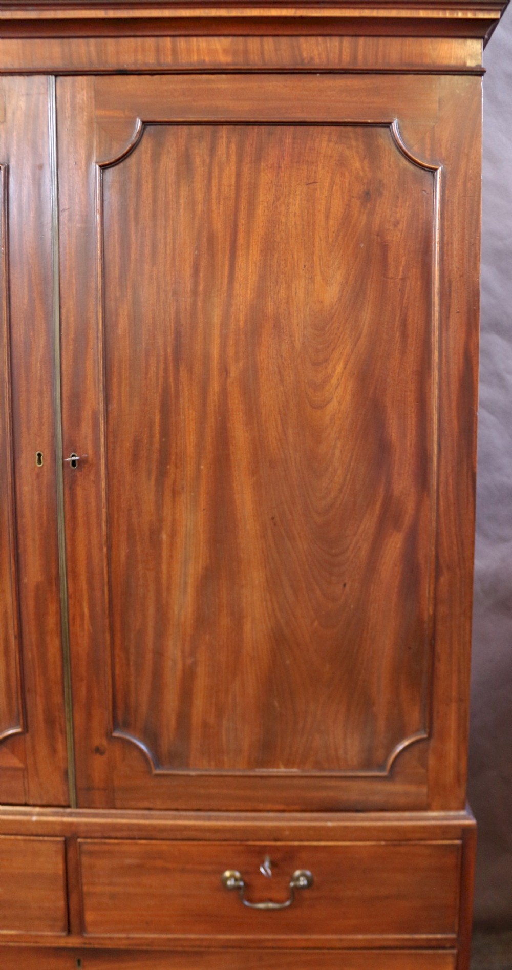 A Georgian mahogany linen press featuring panelled double doors above a chest with two short and two long drawers raised on bracket feet. View VIII