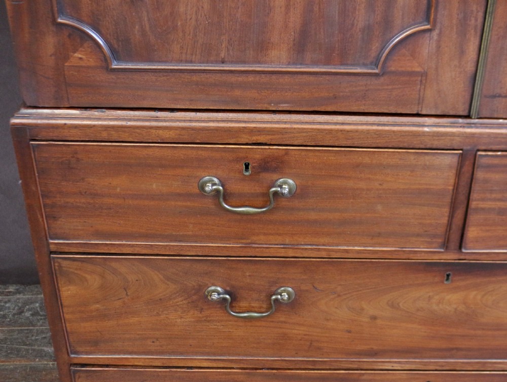 A Georgian mahogany linen press featuring panelled double doors above a chest with two short and two long drawers raised on bracket feet. View IX