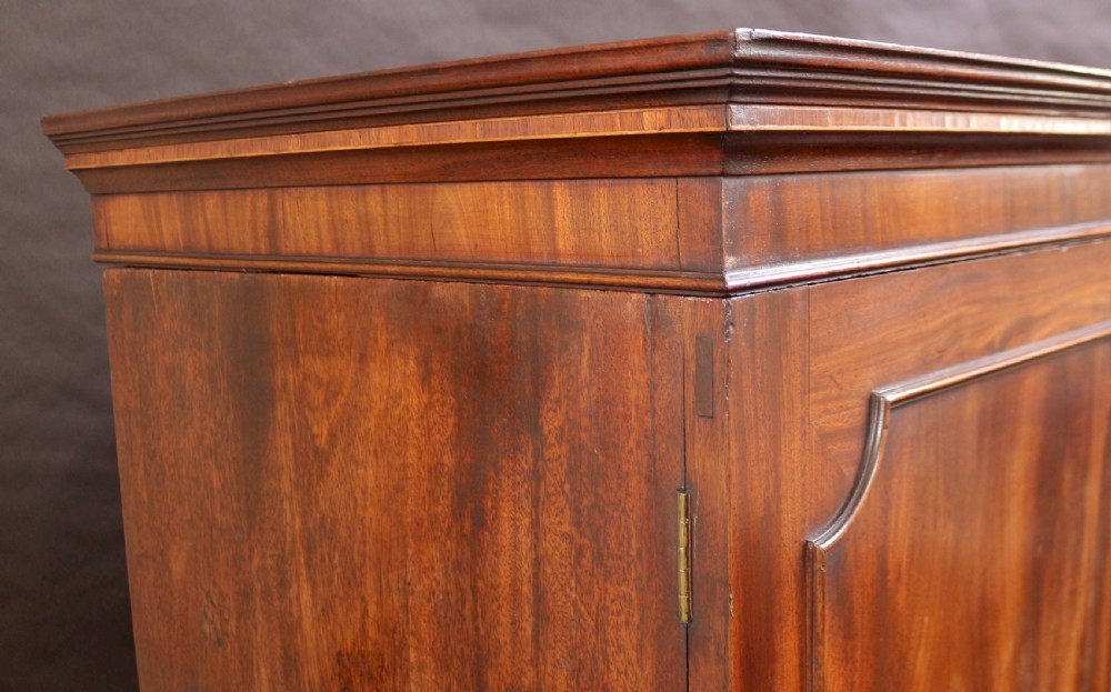 A Georgian mahogany linen press featuring panelled double doors above a chest with two short and two long drawers raised on bracket feet. View XI
