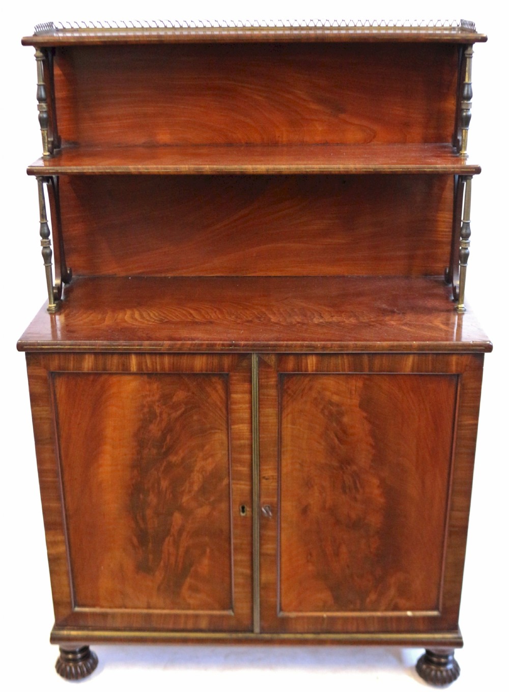 A Regency flame mahogany chiffonier featuring a two-door base cupboard, a two-tier shelf back supported by slender brass pillars, and a pierced brass gallery rail.