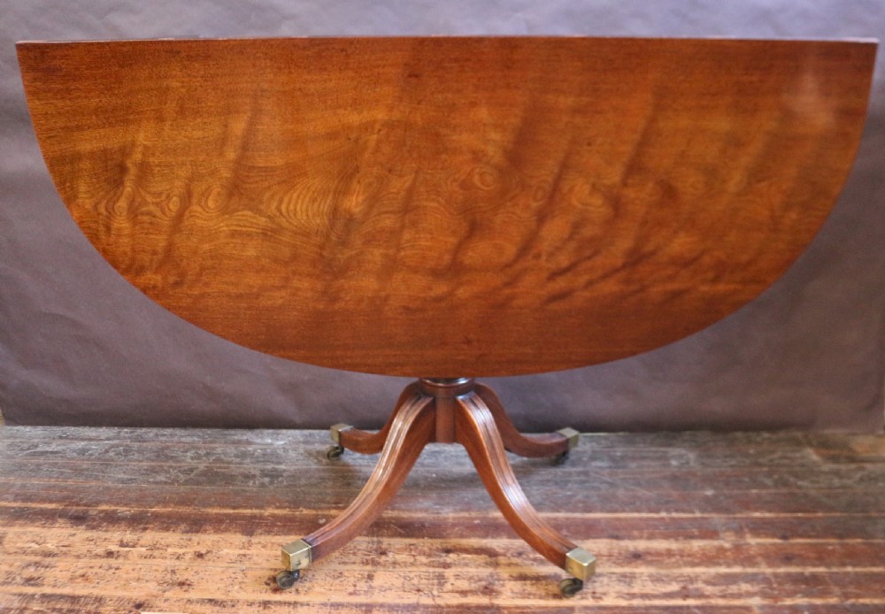 An extending mahogany twin pedestal dining table featuring rounded D-ends, a removable central leaf, reeded splayed legs, and brass castors. View VI