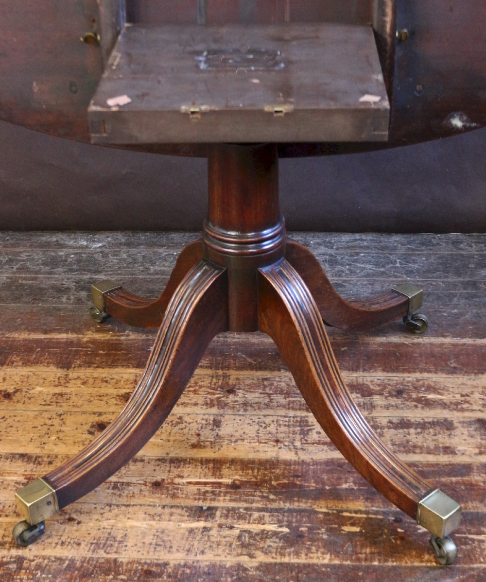 An extending mahogany twin pedestal dining table featuring rounded D-ends, a removable central leaf, reeded splayed legs, and brass castors. View IX