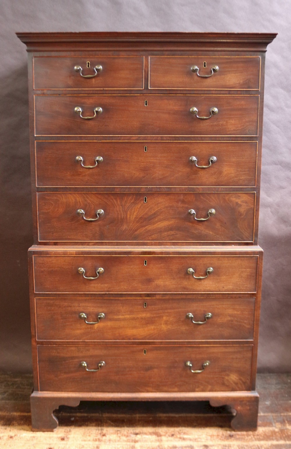 A George III mahogany chest on chest featuring two short over five long graduated drawers with brass swan-neck handles on bracket feet.