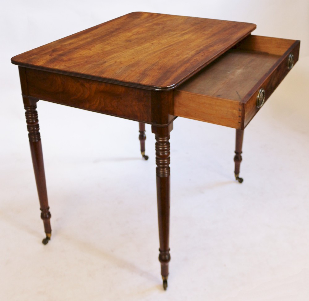 A George IV mahogany side table featuring a single frieze drawer with brass ring handles, turned legs, and brass castors. View III
