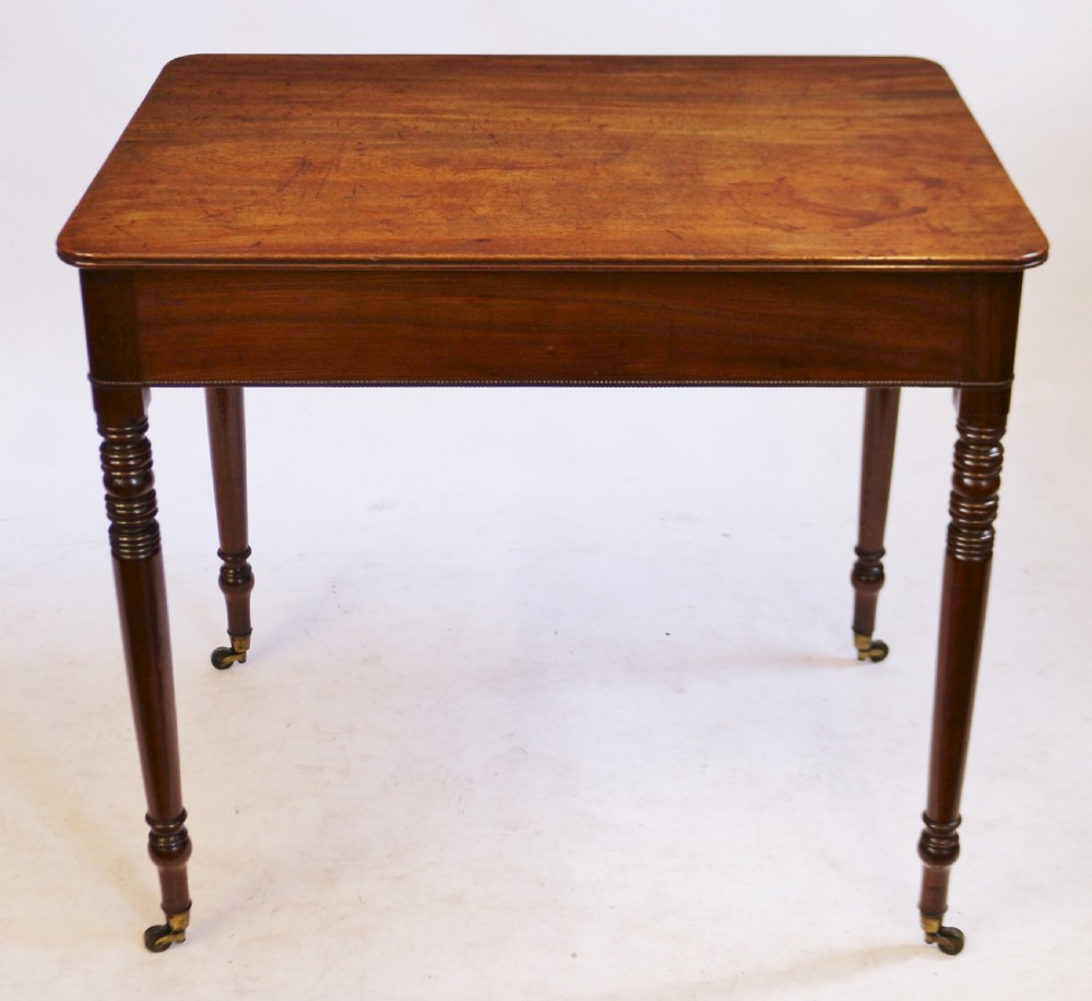 A George IV mahogany side table featuring a single frieze drawer with brass ring handles, turned legs, and brass castors. View VI