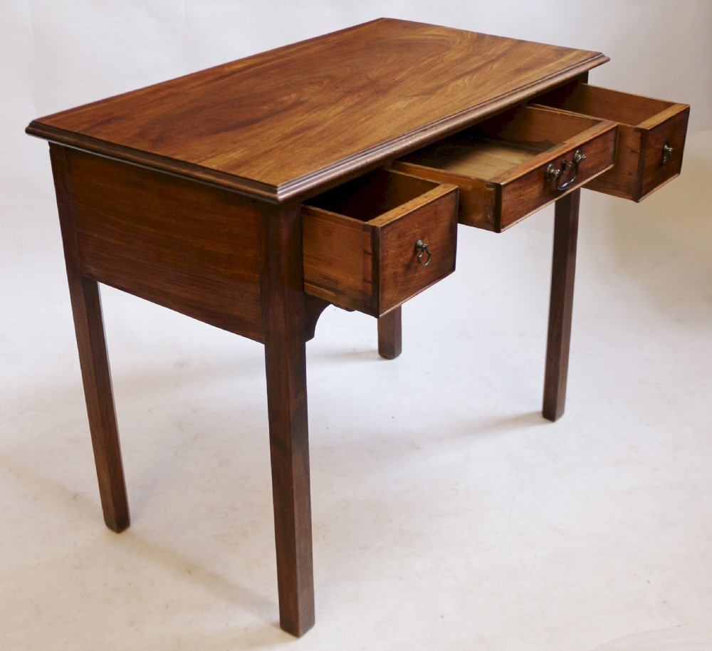 A George III mahogany lowboy table featuring a moulded top over three drawers with brass handles and a scalloped apron on square legs. View II
