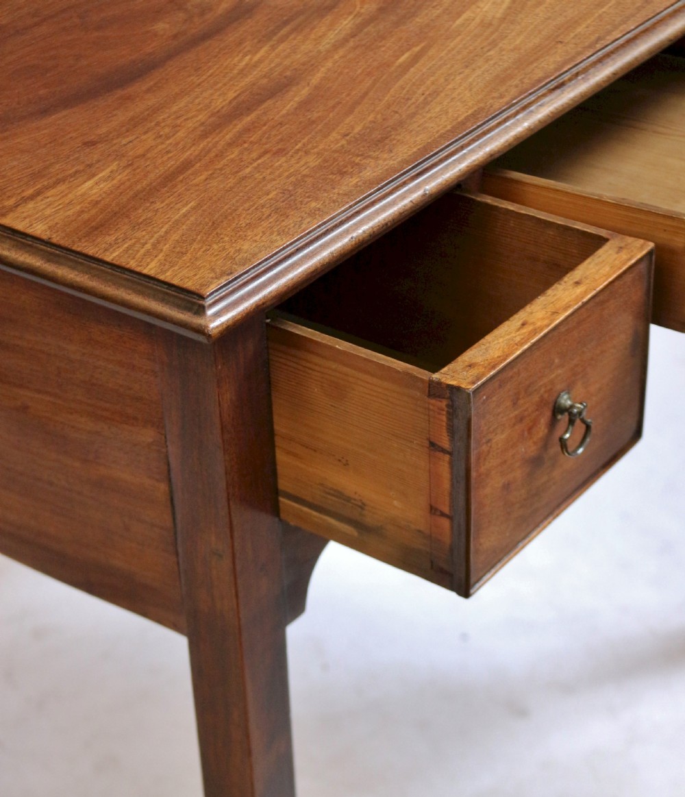 A George III mahogany lowboy table featuring a moulded top over three drawers with brass handles and a scalloped apron on square legs. View VI