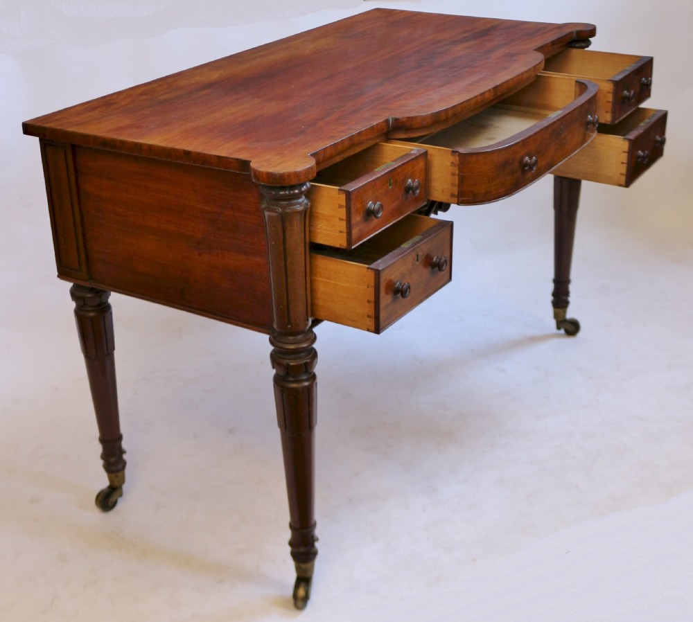 An early Victorian mahogany kneehole desk with five drawers, turned legs on brass castors, and carved corner spandrels. View III