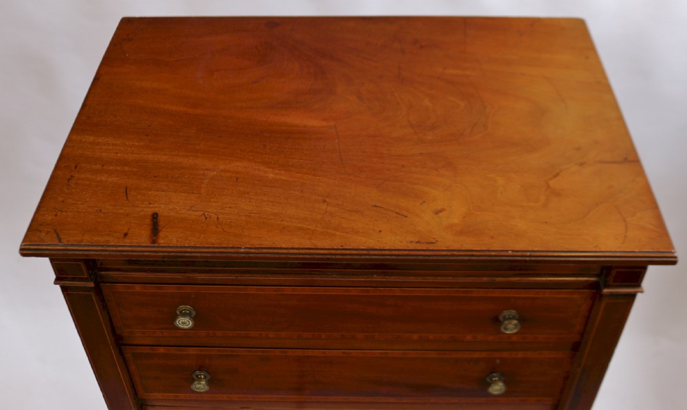 An Edwardian mahogany Wellington chest with seven drawers featuring light wood inlay and small round knobs. View V
