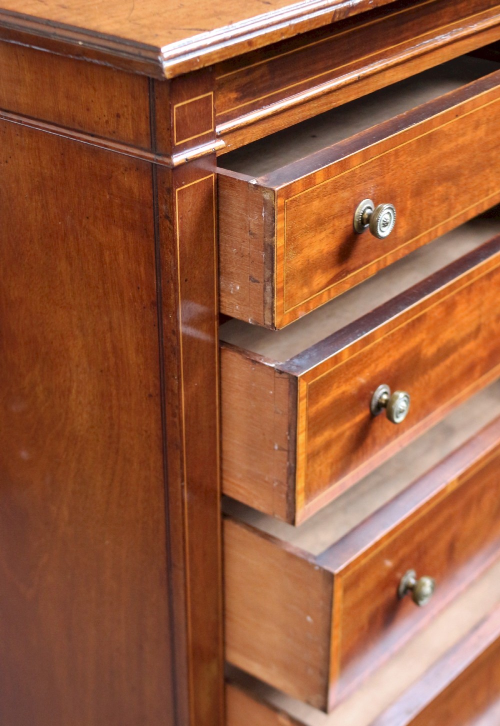 An Edwardian mahogany Wellington chest with seven drawers featuring light wood inlay and small round knobs. View VI