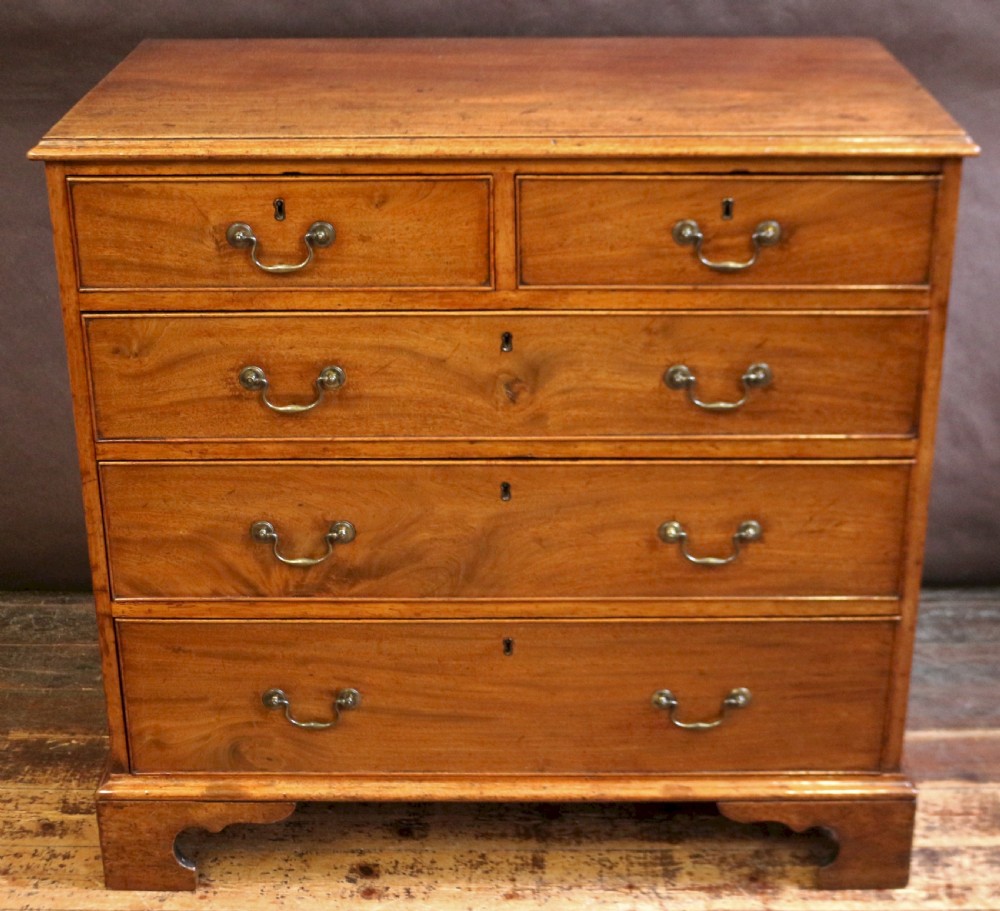 A George III mahogany chest of drawers featuring two short drawers over three long drawers with brass swan-neck handles and bracket feet.