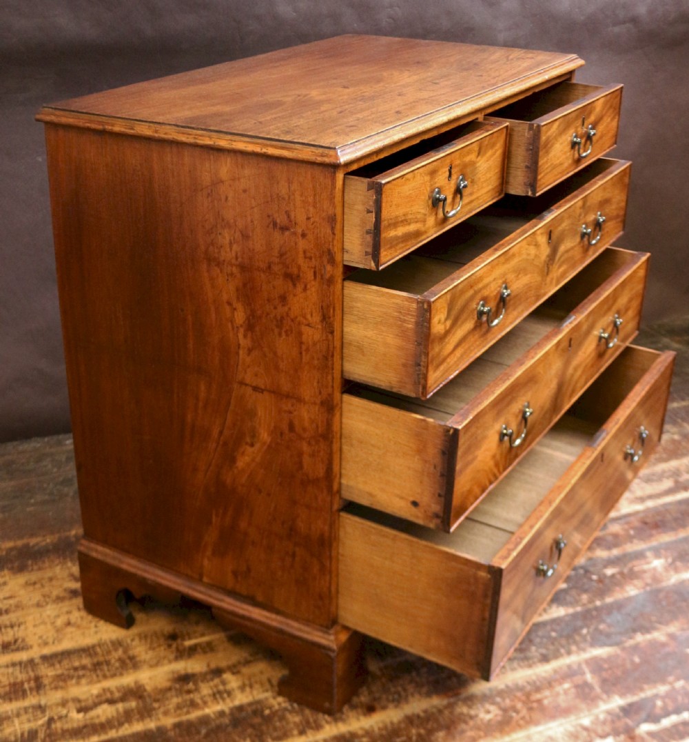 A George III mahogany chest of drawers featuring two short drawers over three long drawers with brass swan-neck handles and bracket feet. View II