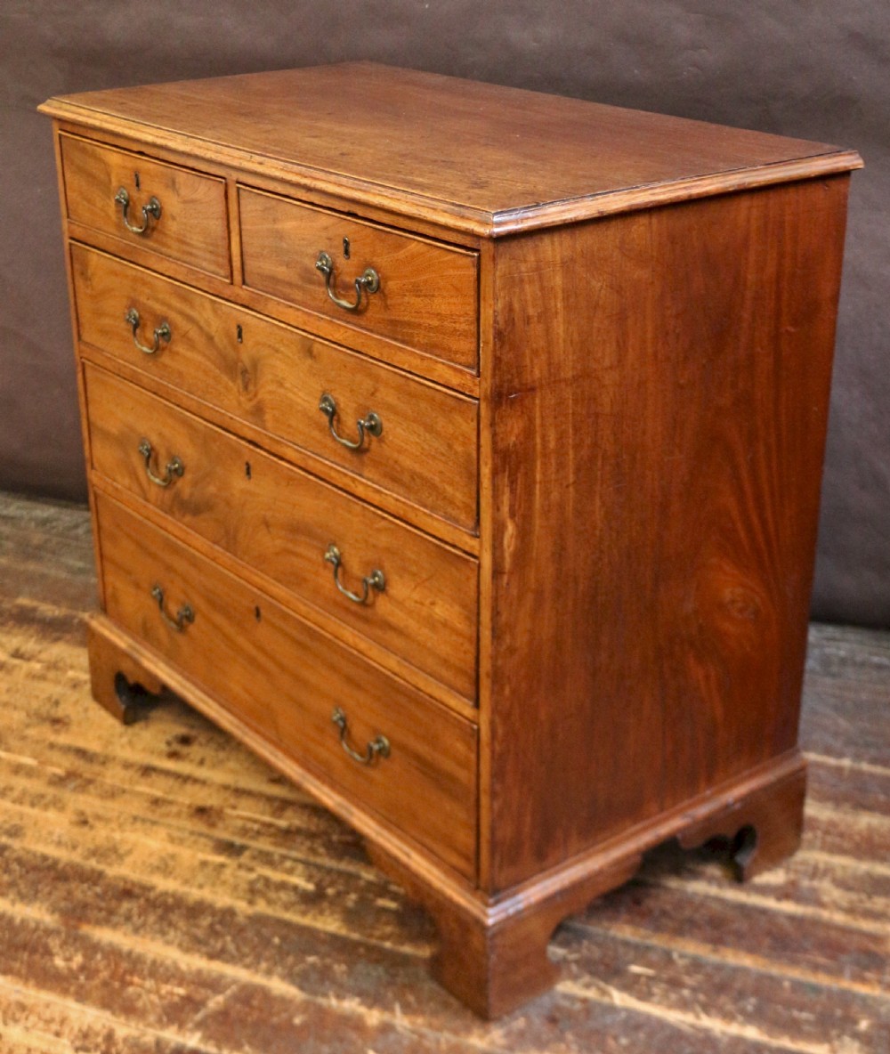 A George III mahogany chest of drawers featuring two short drawers over three long drawers with brass swan-neck handles and bracket feet. View V