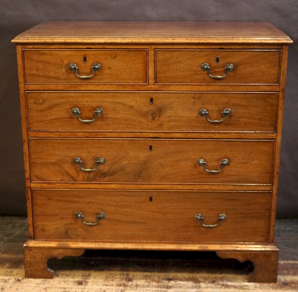 A George III mahogany chest of drawers featuring two short drawers over three long drawers with brass swan-neck handles and bracket feet. View IX