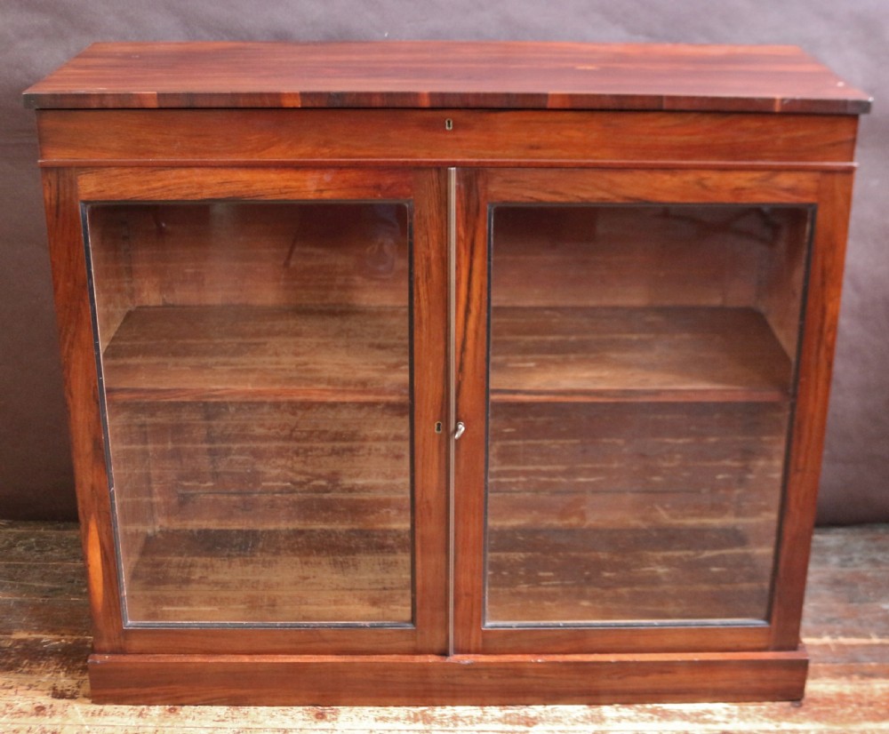 A George IV thuya wood side cabinet featuring two glazed doors, internal shelves, and a solid plinth base.
