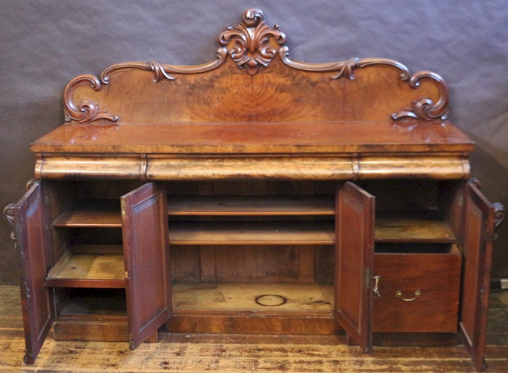 A Victorian mahogany four-door sideboard featuring a scroll-carved backboard, flame mahogany doors, and a solid plinth base. View II