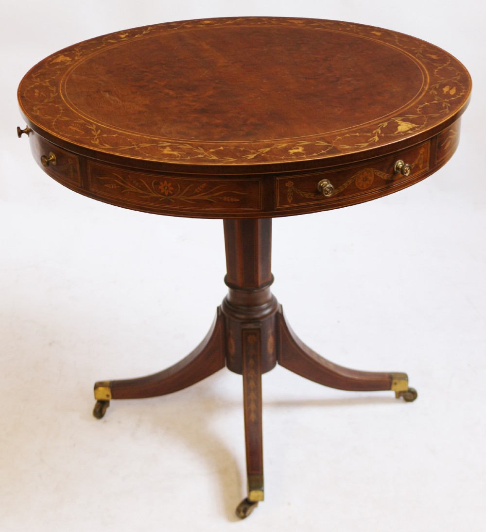 An Edwardian mahogany circular drum table featuring floral and zodiac marquetry inlays, a frieze drawer with dual brass knobs, and a central pedestal resting on four splayed legs with brass castors. View III