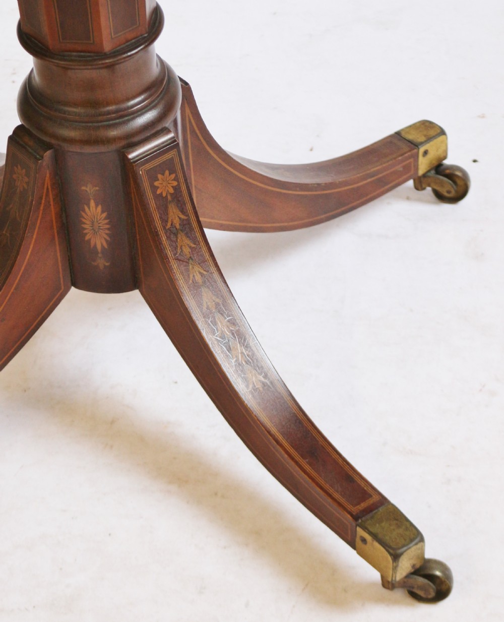 An Edwardian mahogany circular drum table featuring floral and zodiac marquetry inlays, a frieze drawer with dual brass knobs, and a central pedestal resting on four splayed legs with brass castors. View XII