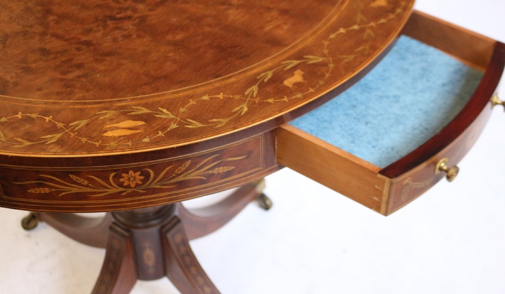 An Edwardian mahogany circular drum table featuring floral and zodiac marquetry inlays, a frieze drawer with dual brass knobs, and a central pedestal resting on four splayed legs with brass castors. View XIII