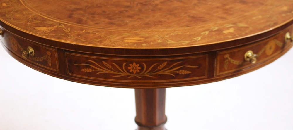 An Edwardian mahogany circular drum table featuring floral and zodiac marquetry inlays, a frieze drawer with dual brass knobs, and a central pedestal resting on four splayed legs with brass castors. View XIV