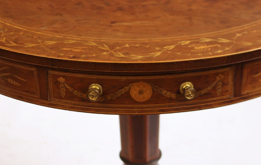 An Edwardian mahogany circular drum table featuring floral and zodiac marquetry inlays, a frieze drawer with dual brass knobs, and a central pedestal resting on four splayed legs with brass castors. View XV