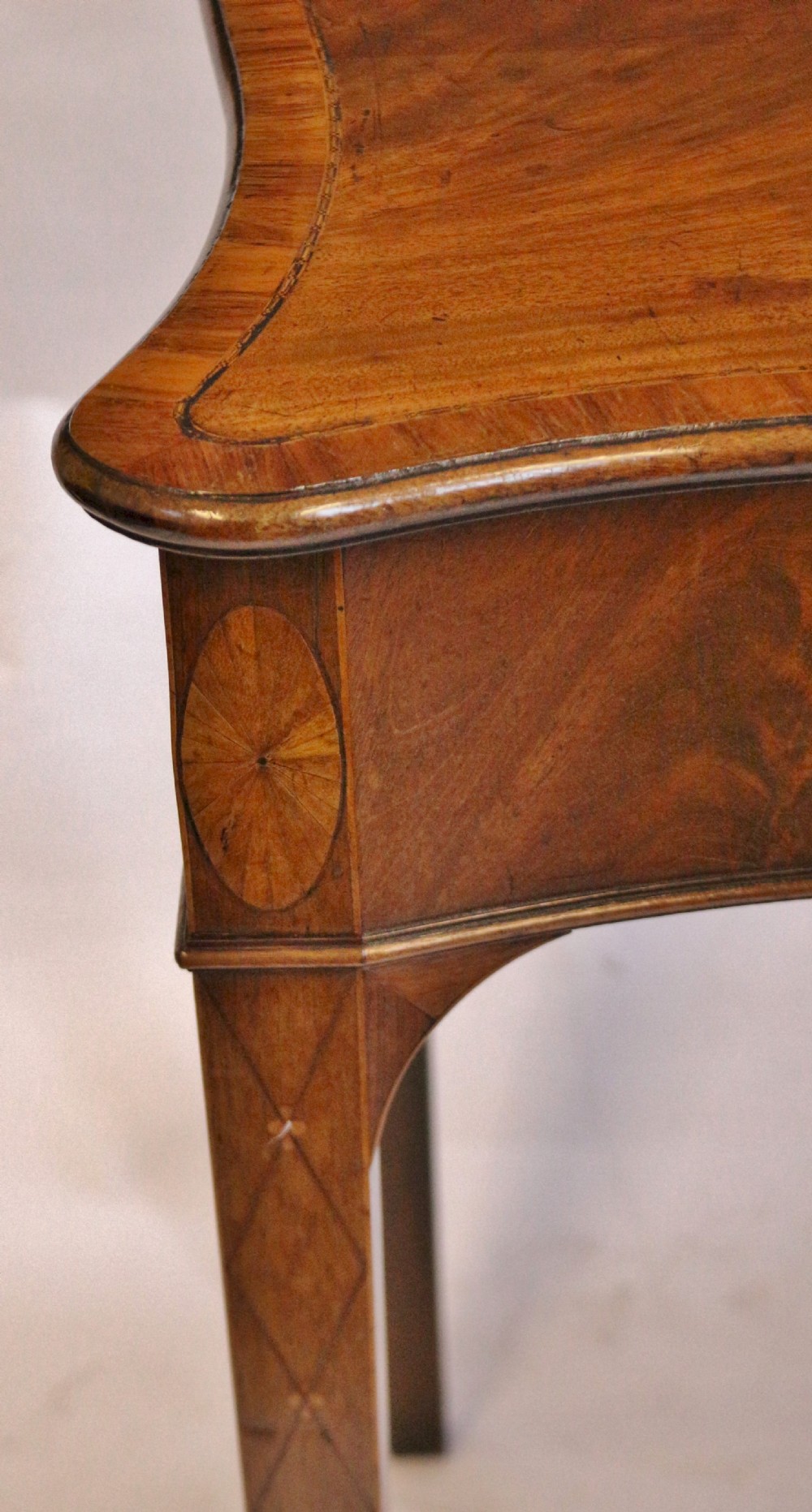 A George III mahogany serving table with a wavy serpentine front, flame mahogany veneer, and four tapered square legs. View VII