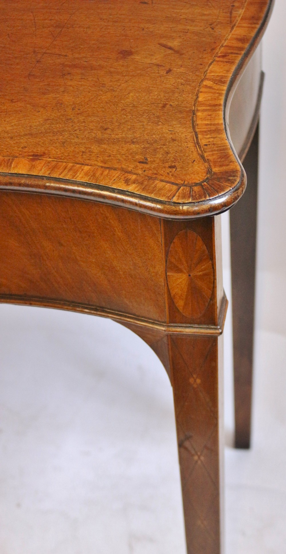 A George III mahogany serving table with a wavy serpentine front, flame mahogany veneer, and four tapered square legs. View VIII