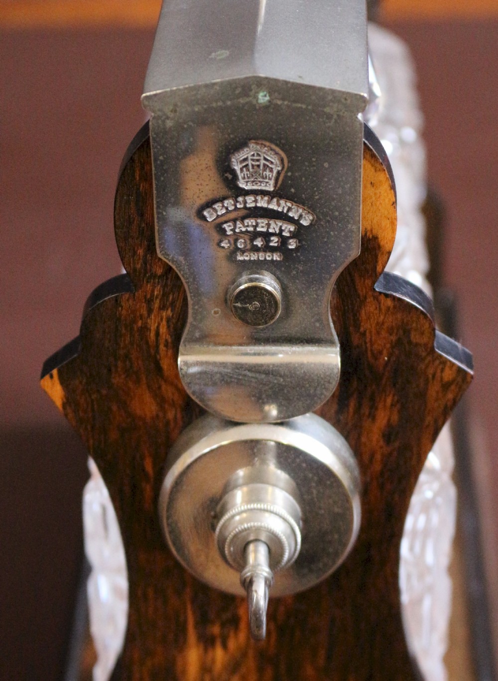 A late Victorian three-bottle tantalus constructed from dark figured coromandel wood with silver-plated corner mounts and three square cut-crystal decanters with faceted stoppers. View VI