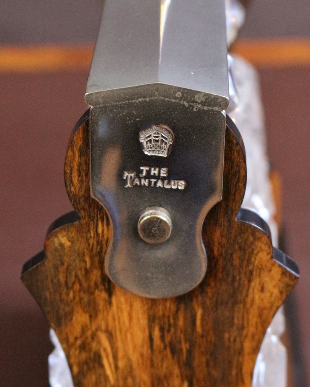 A late Victorian three-bottle tantalus constructed from dark figured coromandel wood with silver-plated corner mounts and three square cut-crystal decanters with faceted stoppers. View VII