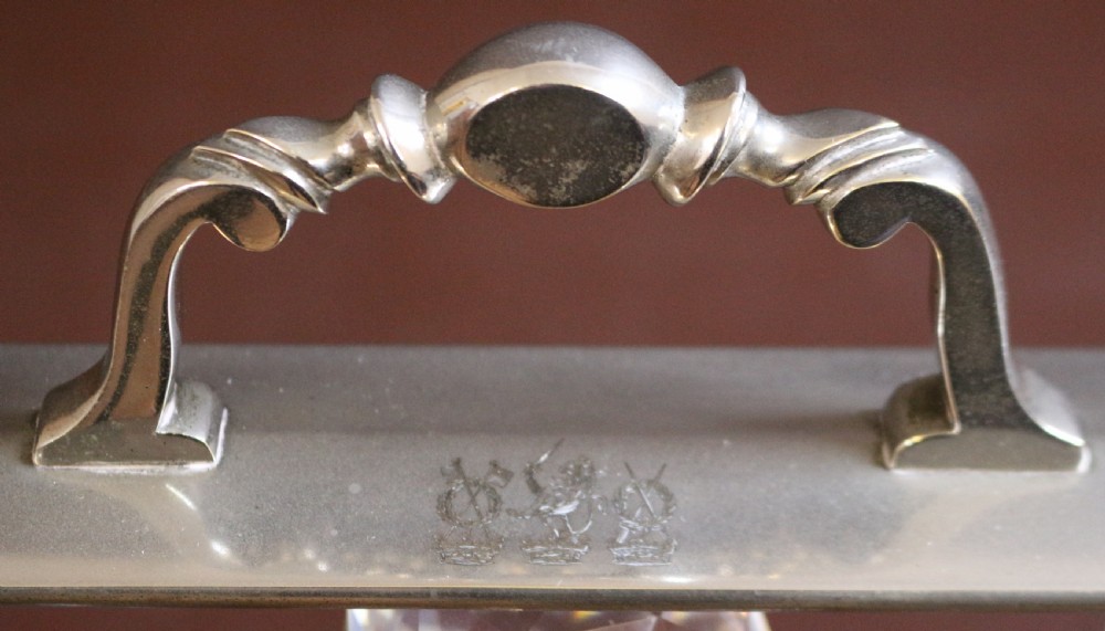 A late Victorian three-bottle tantalus constructed from dark figured coromandel wood with silver-plated corner mounts and three square cut-crystal decanters with faceted stoppers. View XII