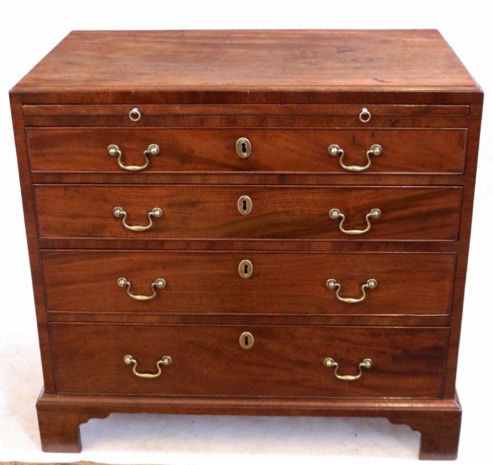A Georgian mahogany chest of drawers featuring four graduated long drawers with brass swan-neck handles, a pull-out brushing slide, and classic bracket feet.