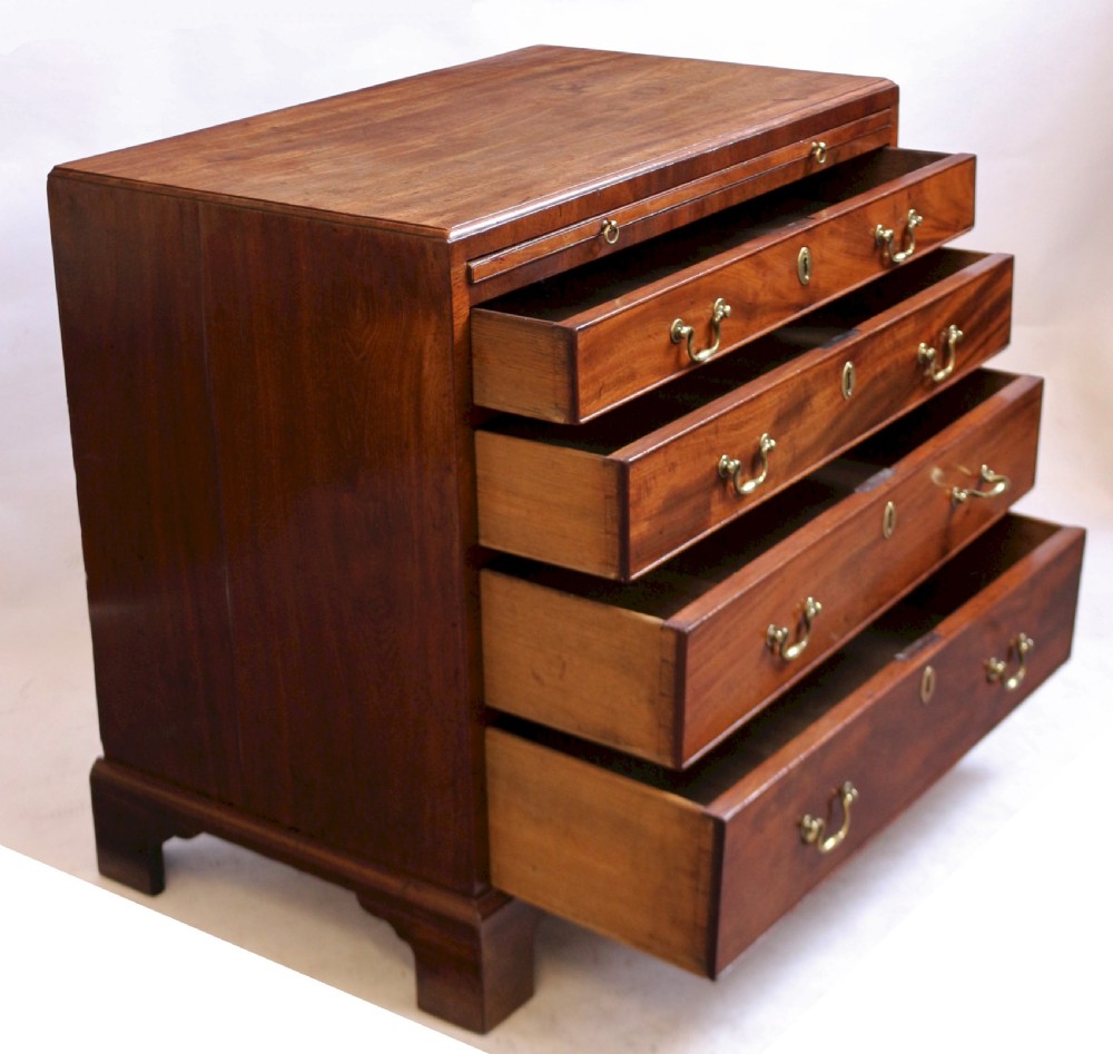 A Georgian mahogany chest of drawers featuring four graduated long drawers with brass swan-neck handles, a pull-out brushing slide, and classic bracket feet. View V