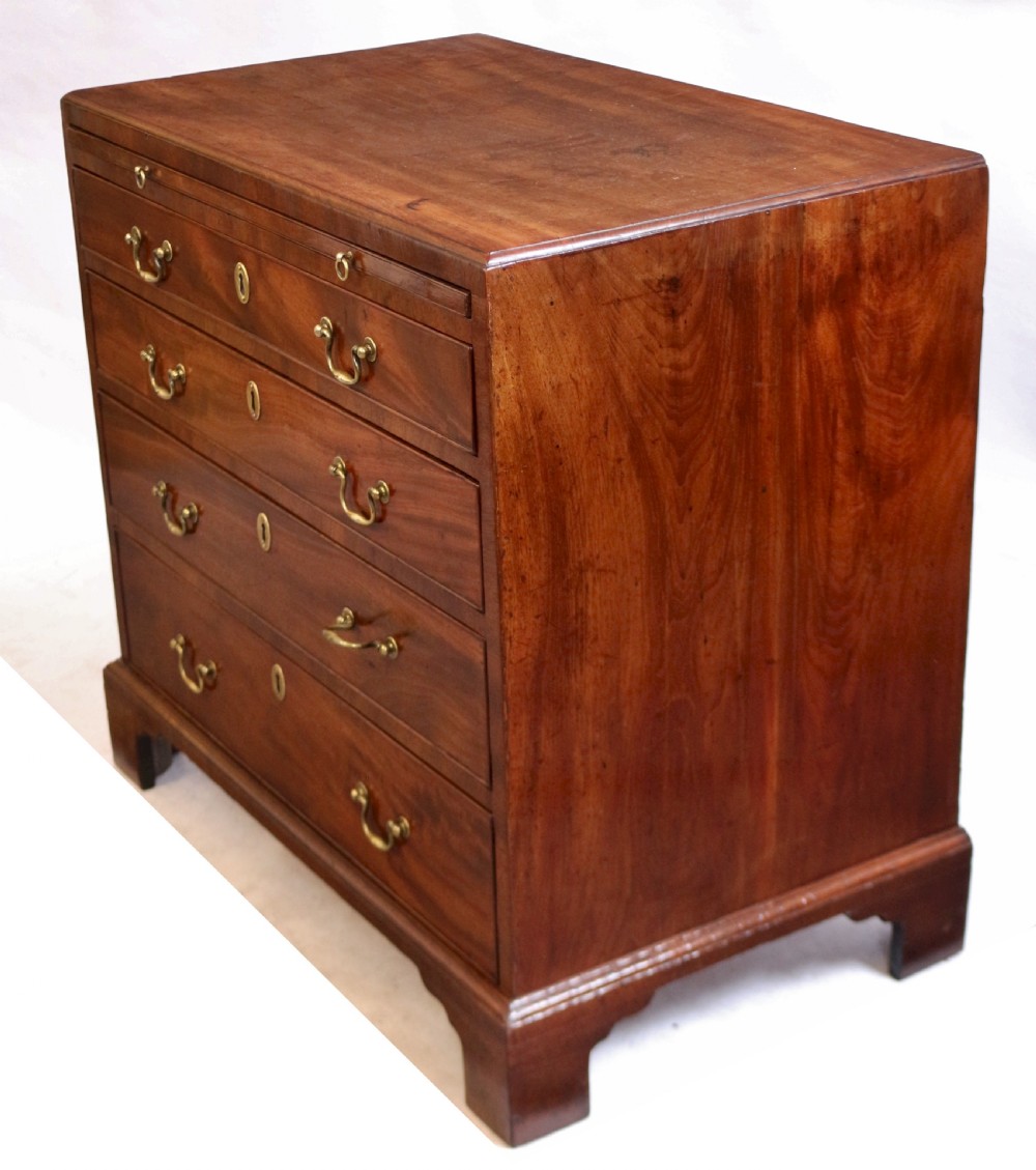 A Georgian mahogany chest of drawers featuring four graduated long drawers with brass swan-neck handles, a pull-out brushing slide, and classic bracket feet. View VI
