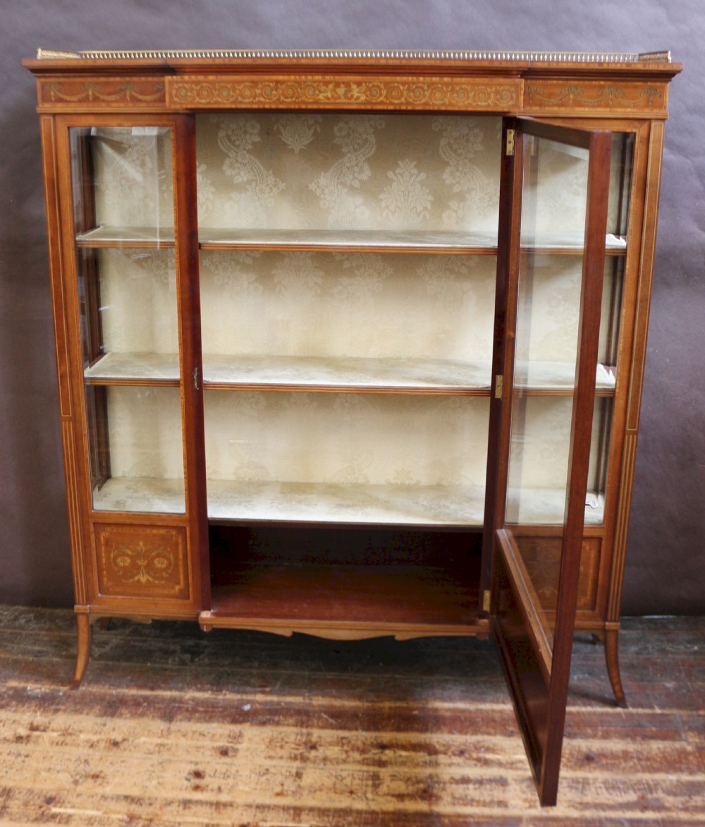 An antique mahogany display cabinet featuring satinwood floral marquetry, a single glazed door, side window panels, and a brass gallery along the top edge. View II