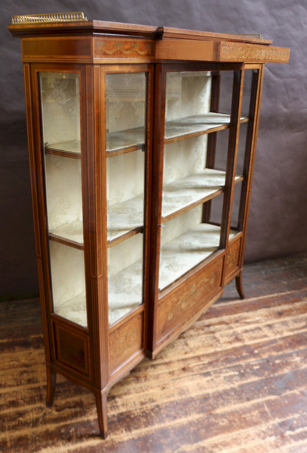 An antique mahogany display cabinet featuring satinwood floral marquetry, a single glazed door, side window panels, and a brass gallery along the top edge. View III