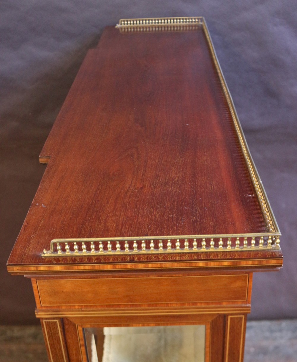 An antique mahogany display cabinet featuring satinwood floral marquetry, a single glazed door, side window panels, and a brass gallery along the top edge. View V