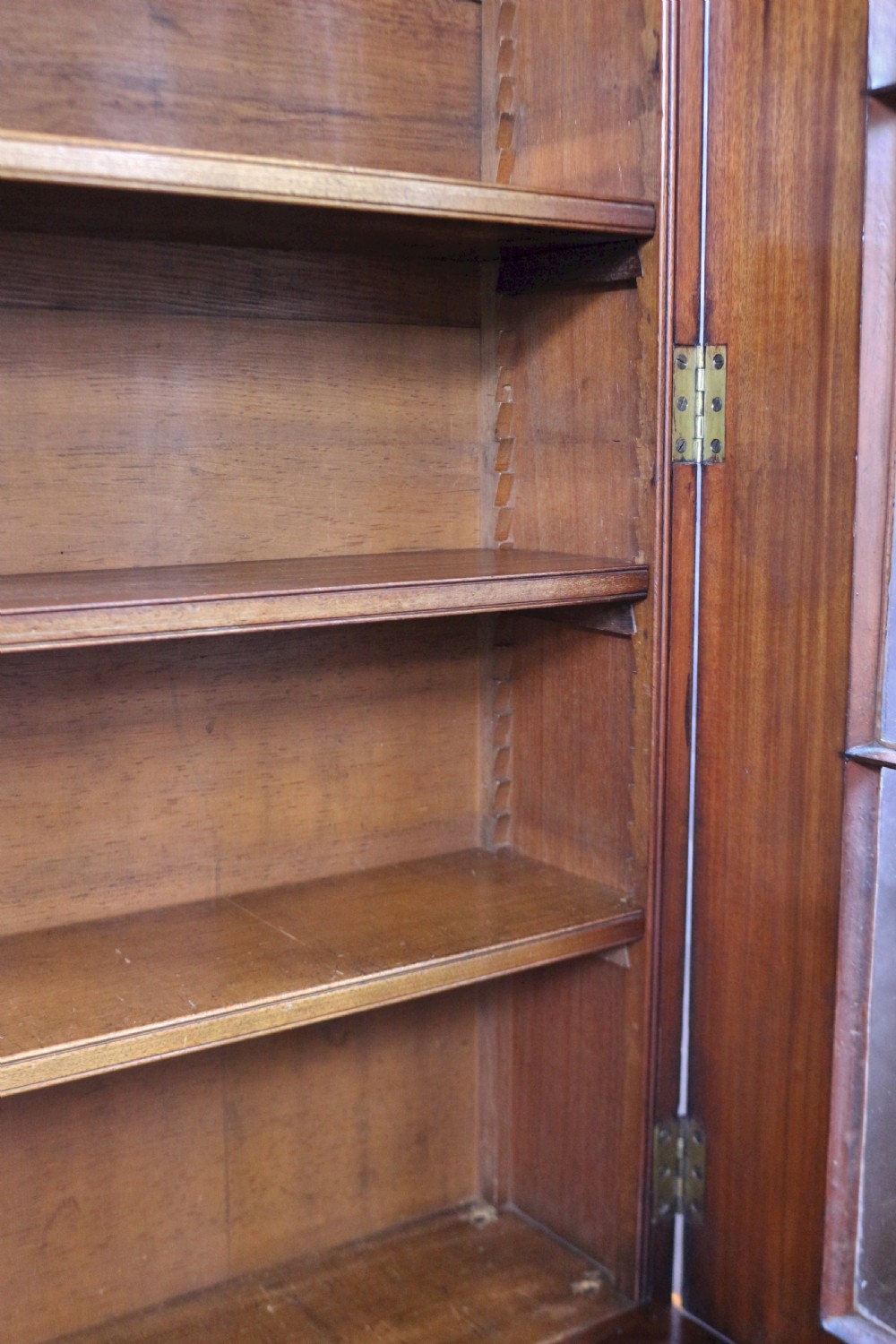 A George IV mahogany bookcase featuring a two-door astragal glazed upper section with gothic arch panes above a two-door cupboard base with flame mahogany grain patterns. View VIII