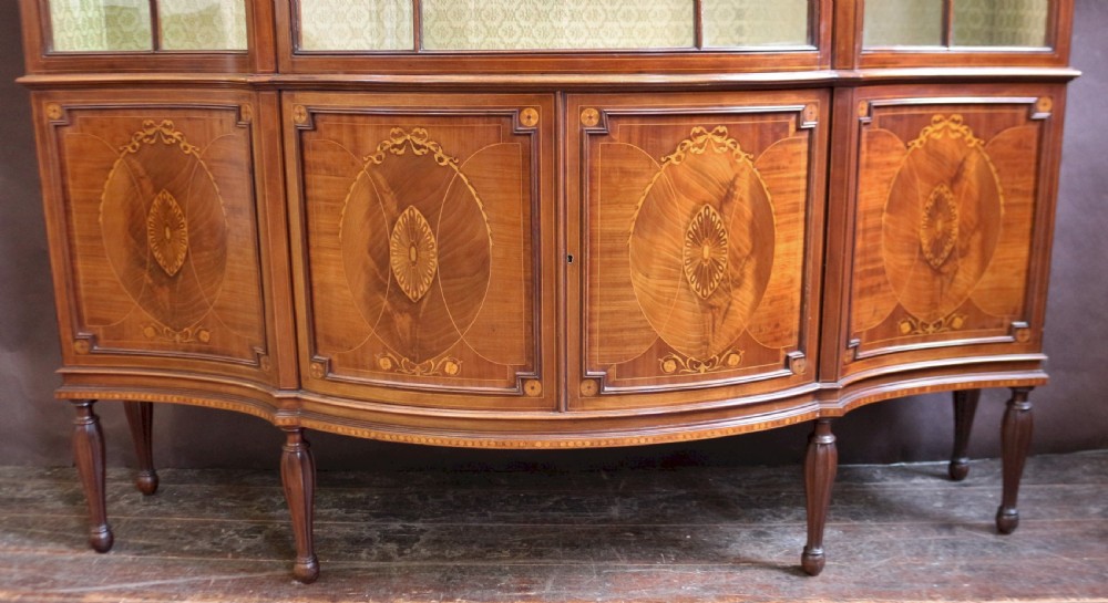 A late 19th-century mahogany display cabinet featuring three glazed doors with curved astragal glazing bars above inlaid lower panels and turned legs. View VI