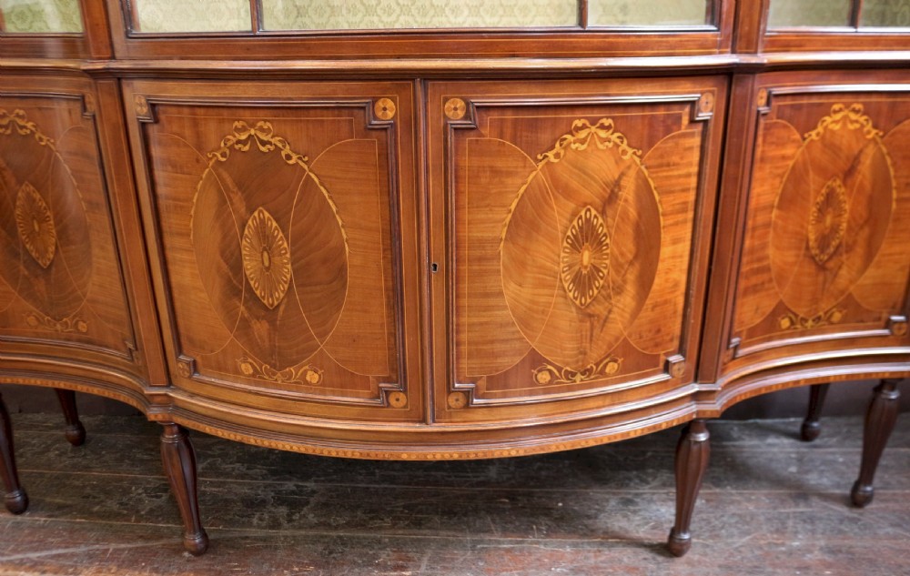 A late 19th-century mahogany display cabinet featuring three glazed doors with curved astragal glazing bars above inlaid lower panels and turned legs. View VIII