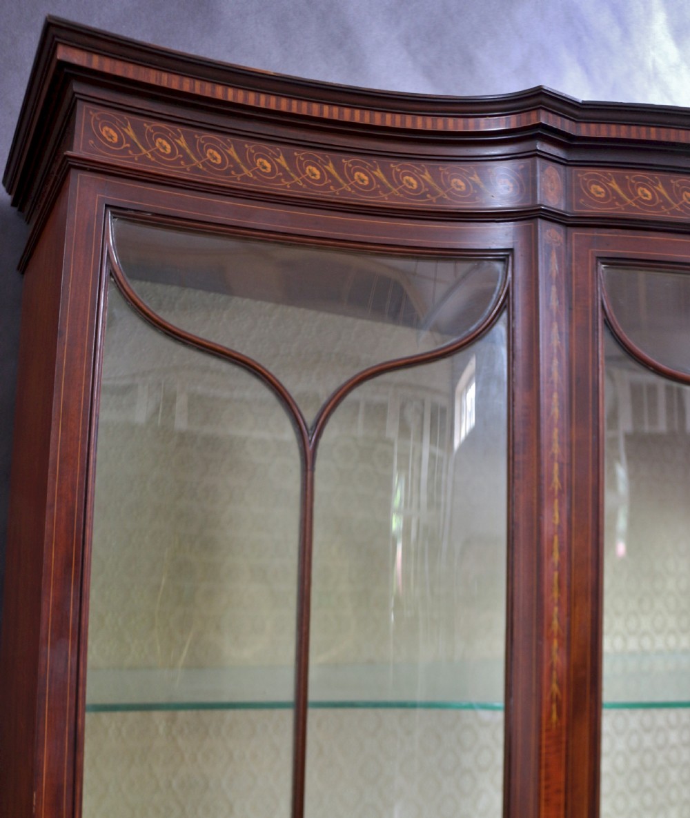 A late 19th-century mahogany display cabinet featuring three glazed doors with curved astragal glazing bars above inlaid lower panels and turned legs. View XII