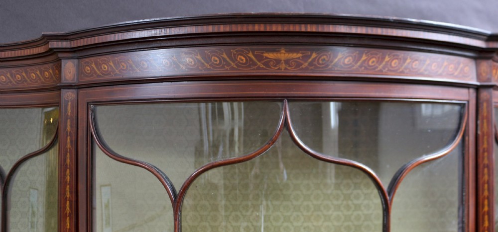A late 19th-century mahogany display cabinet featuring three glazed doors with curved astragal glazing bars above inlaid lower panels and turned legs. View XIII