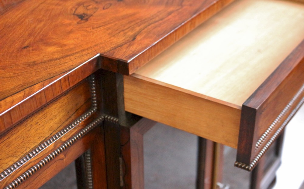 An antique Regency rosewood breakfront side cabinet featuring four glazed doors, a brass gallery rail along the top, and turned fluted feet. View IX
