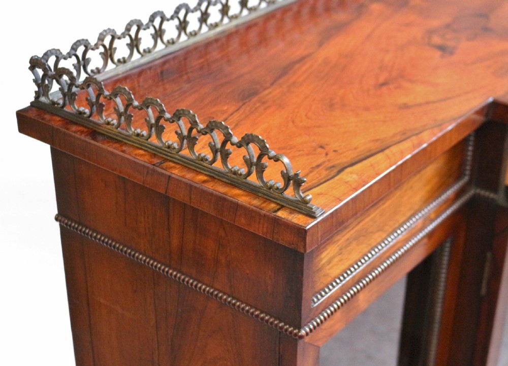 An antique Regency rosewood breakfront side cabinet featuring four glazed doors, a brass gallery rail along the top, and turned fluted feet. View XI