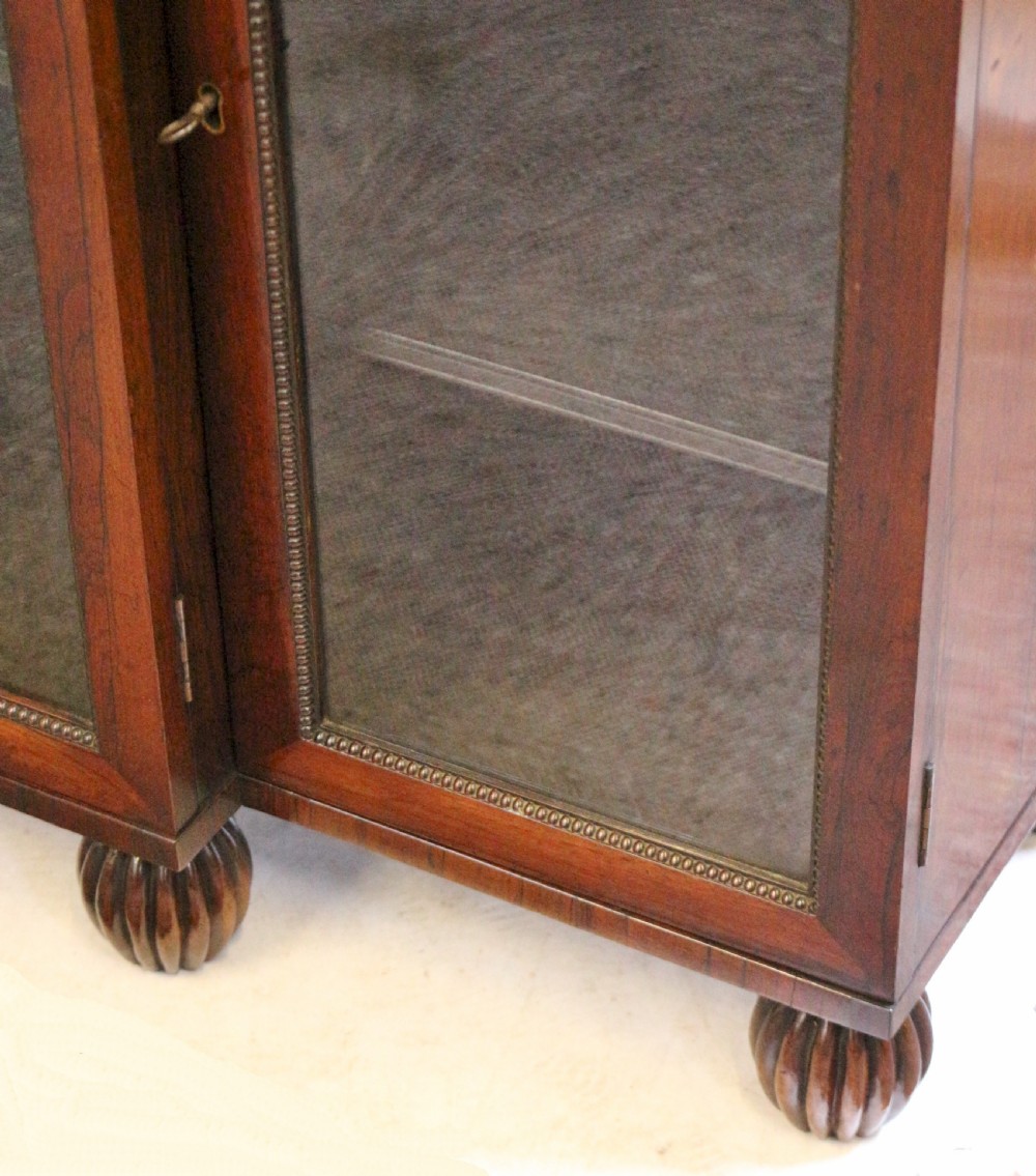 An antique Regency rosewood breakfront side cabinet featuring four glazed doors, a brass gallery rail along the top, and turned fluted feet. View XII