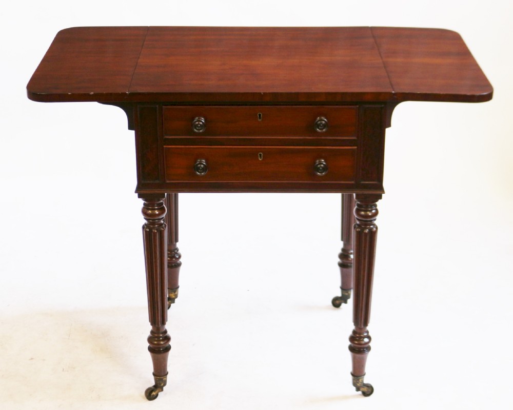 A William IV mahogany drop-leaf side table featuring two drawers with turned knobs, brass keyhole escutcheons, and reeded legs on brass castors. View II