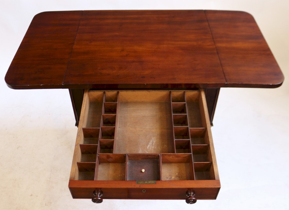 A William IV mahogany drop-leaf side table featuring two drawers with turned knobs, brass keyhole escutcheons, and reeded legs on brass castors. View III