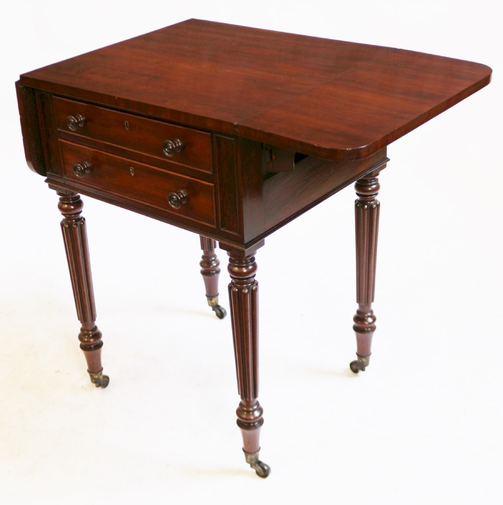 A William IV mahogany drop-leaf side table featuring two drawers with turned knobs, brass keyhole escutcheons, and reeded legs on brass castors. View V